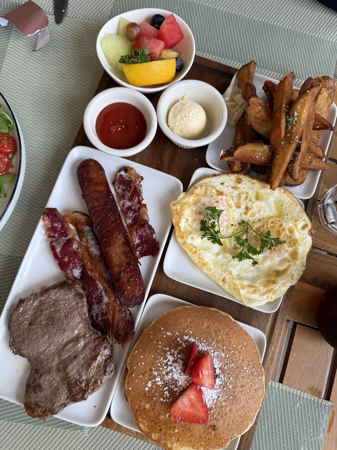 American breakfast with steak, bacon, sausage, pancake and eggs